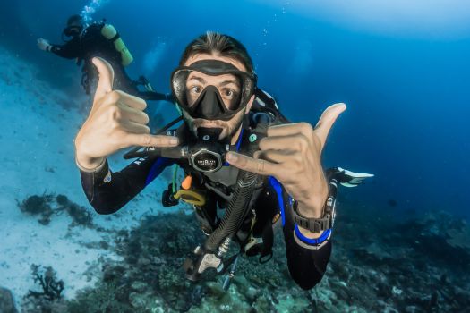 Un plongeur sous l'eau faisant des signes avec les mains